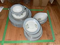 Full top view of stacked floral patterned dishes and bowls with labels visible on floor