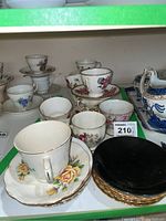 Assortment of floral porcelain tea cups with matching saucers, varying floral designs, gold trim