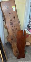 Photo of a wooden crib board bench seat with drilled holes, leaning against a door. Shows scratches and natural wood knots.