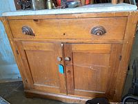 Front view of wood chest with single drawer and double-door lower storage, marble top visible with scratches and dirt.