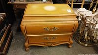 Front angled view of the wooden dresser showing two drawers with decorative metal handles and curved legs with carved details.