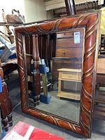 Front view of large wood framed mirror showing carved groove detailing and reddish-brown finish.