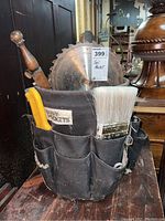 Viewing tool bucket filled with paint brush, hammer, and saw blades from the front angle