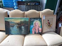 Wide shot of all three wall art pieces displayed on a cream sofa.