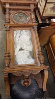 Full view of the wooden wall clock laying flat, showing overall condition and structure including clock face and glass door lower section.