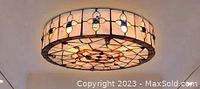 Craftsman style stained glass ceiling light fixture mounted and lit, front view.