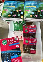 Top-down view of assorted Christmas light boxes showing LED multi-color string lights, net light sets, and an icicle light set, all in retail packaging.