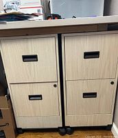Front view of two small file cabinets side-by-side, showing drawer fronts, handles, and locks on lower drawers.