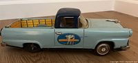 Side view of the vintage tin Ford truck toy showing truck bed and horse decal on door