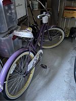Photo showing the purple adult women's cruiser bike, highlighting the left side with yellow sidewall tires, white seat with floral designs, and purple rear fender.