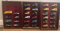 Photo showing 32 Matchbox 'Days Gone' diecast delivery trucks displayed on three wooden wall shelves with mounting arms.