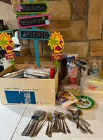Photo showing wooden yard decoration sign with summer fun theme and chips & dip bowls, disposable cups, cutlery, and table linens in box and on table.