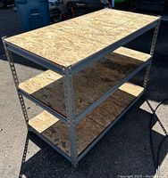 Front and top view of a metal framed shop storage shelf with particle board surfaces.