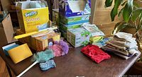 Photo of various Swiffer cleaning supplies arranged on a table including duster refills, microfiber dusters, cleaning cloths, and boxes of pads.
