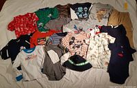 Full spread of assorted baby boy clothing including shirts, pajamas, pants, and footed sleepers in various colors and prints