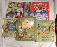 Photo of all 7 books arranged on a surface showing front covers including English and French titles, sound buttons visible on one book.