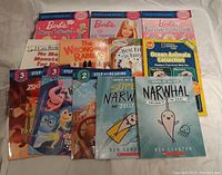 Photo of all books laid out showing variety of titles and themes including Barbie, Inside Out, Narwhal and Jelly, Ocean Animals, and others.