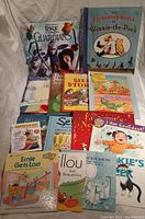 Full grouping of assorted children's books including colorful illustrated paperbacks and hardcovers spread out on a white sheet.