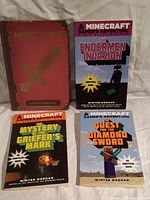 Photo showing four Minecraft books: a hardcover Combat Handbook and three unofficial novels.