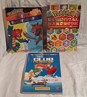 Three books: Pokemon Super Showdowns, Pokemon Essential Handbook, Disney Club Penguin guide.