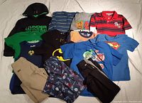 All 12 pieces of boys clothing including hoodies, T-shirts, polo, tank top, and pants laid flat.