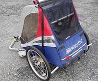 Rear and side view of the Chariot bike trailer highlighting the foldable frame, wheels, and fabric covering.