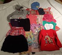 Photo of assorted girls size 4 clothing including hoodies, skirts, pants, t-shirts, and a blue hat.