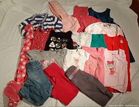 Photo showing a laid out collection of girls size 5 clothing including tops, pants, hoodie, and robe