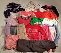 Full view of assorted girls size 5 clothing laid out, including tops, pants, pajamas, and hoodies.