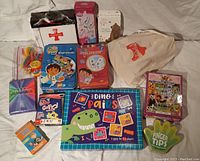 Photo of assorted kids card games, craft items, and a cloth bag of wooden animal dominoes.
