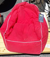 Red Lounge & Co. Red Cliff bean bag chair with attached tag, visible dirt, and wear on fabric.