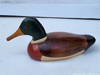 Side view of the vintage carved duck decoy showing detailed paint and wood grain.