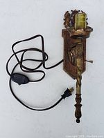 Front view of the antique cast iron wall mount light with electrical cord and plug visible