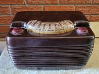 Frontal view showing radio's dark brown Bakelite casing, horizontal grill, and control knobs.