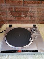Front view of Hitachi HT-2 turntable with open dust cover showing platter, tonearm, and control panel.