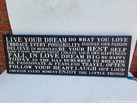 Full view of the large rectangular canvas with white inspirational text on black background, laid against a white backdrop. Text is fully visible and clear.