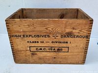 Front angled photo of wooden crate showing stencil marking indicating hazardous contents.