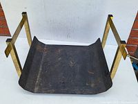 Front view of vintage firewood holder showing curved black tray and gold-toned frame on white backdrop