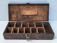 Open wooden box showing 12 small internal compartments made from wood, used condition with visible wear.