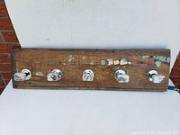 Front view of rustic wooden coat hook board with five marble hooks.