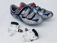 Pair of SiDi cycling shoes size 42 along with white cycling pedals on white background.
