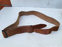 Full view of brown suede guitar strap laid out, showing length and general condition.