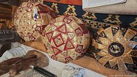 Two large red and cream footstools with gold Egyptian designs and one smaller black and tan footstool with gold embossing shown together.