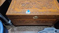 Front and top angled view showing lid carving, side carving and brass lock
