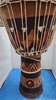 Close-up of upper drum body showing detailed hand carved wood and painted black and red geometric patterns with tight rope tuning.