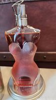 Close up photo of the Lady Bodice shaped perfume bottle showing frosted glass and pinkish-red liquid inside