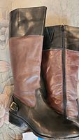 Side view of Ralph Lauren riding boots showing brown and black leather, side zipper, and buckle detail.