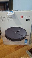 Front of the box showing Roborock E4 branding and image of the robot vacuum mop with app interface on smartphone.