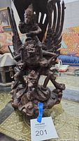 Full view of the Indonesian wood carving sculpture showing multiple figures and wings on a carved base.