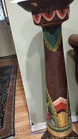 Side view of the carved cylindrical column painted with colorful designs including floral and geometric shapes. Shows part of the base and top.